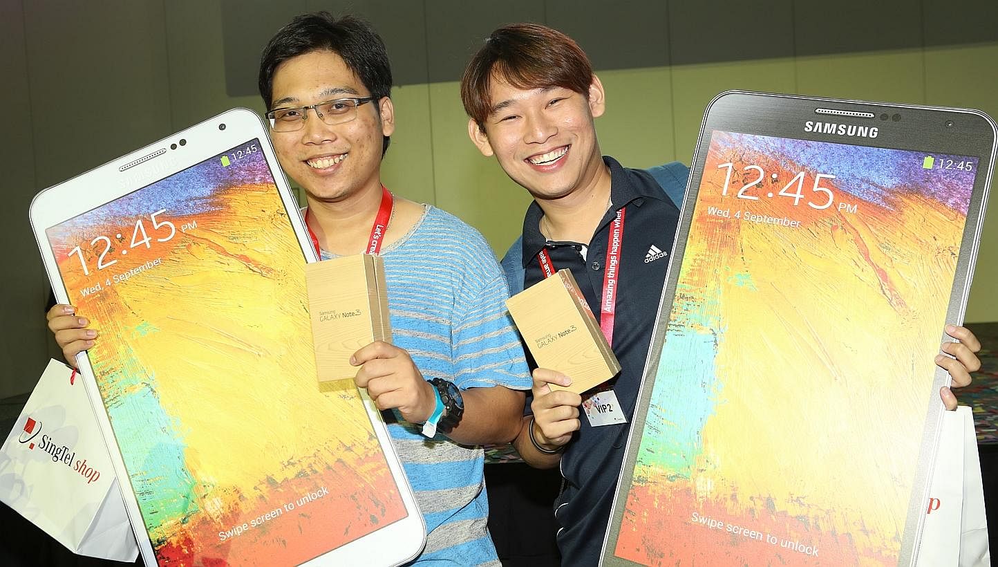 Aesel James (left) and Gedeon Goh are the first two customers in the SingTel queue. -- PHOTO: SINGTEL