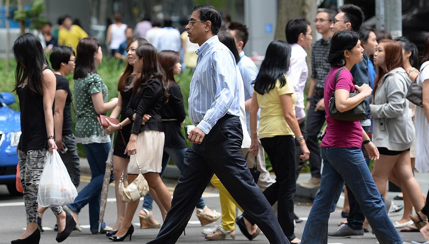 Office workers and pedestrians crossing the road at Raffles Place.&nbsp;Singapore's economy is gradually regaining its upward momentum as the developed nations recover, prompting the central bank to tip "modest growth" for the local economy this year