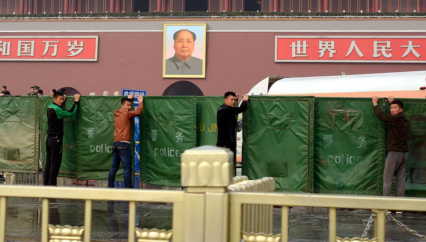 Plainclothes police hold barriers before the scene of a car crash at Tiananmen Gate in Beijing on October 28, 2013. -- PHOTO: AFP