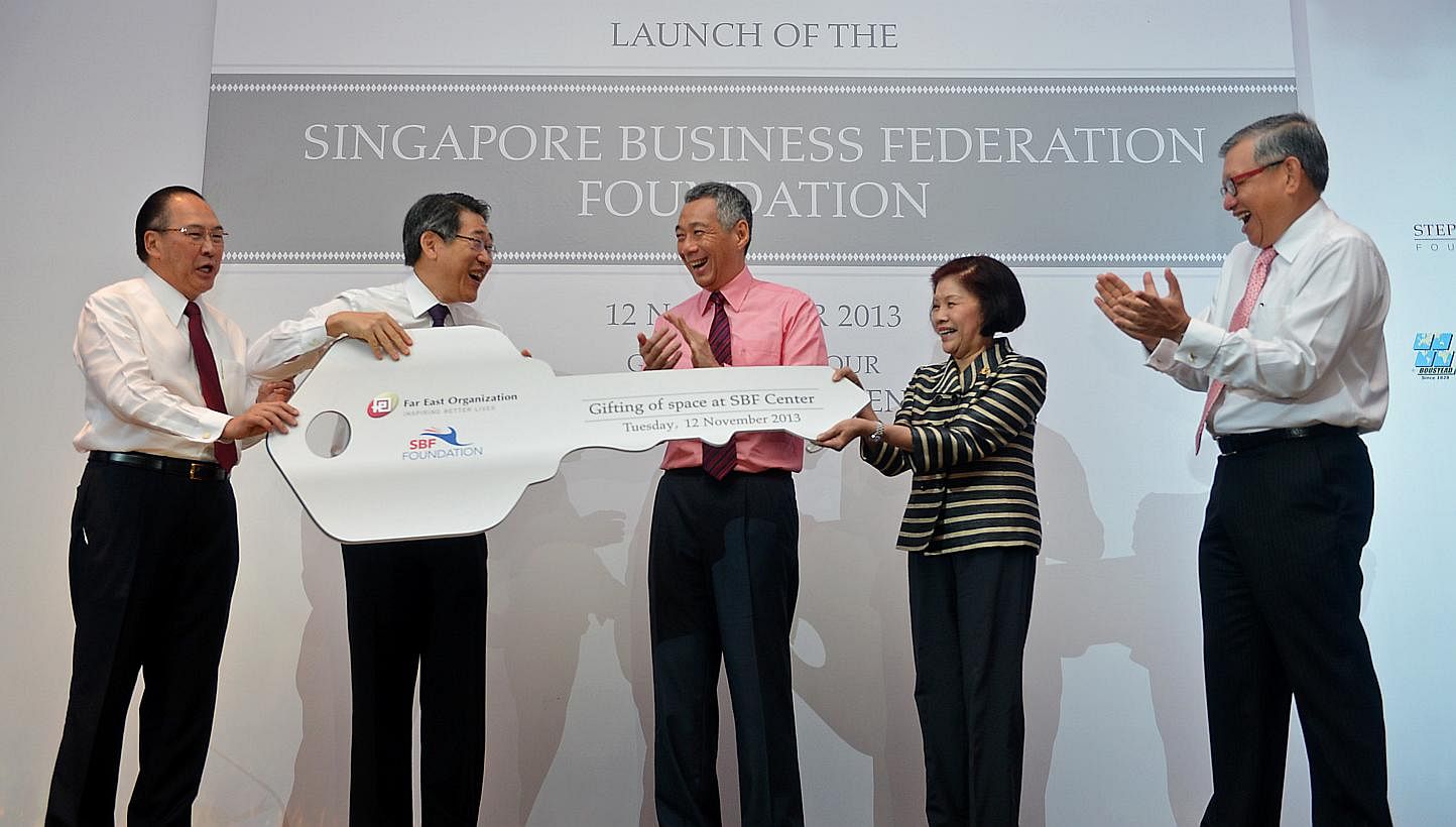 Prime Minister Lee Hsien Loong (centre), Mr Tony Chew (left), Council Chairman of Singapore Business Federation (SBF), and Mr Ho Meng Kit (right), CEO of SBF, witnessing the presentation of a huge key from Mr Philip Ng (second from left), CEO of Far 
