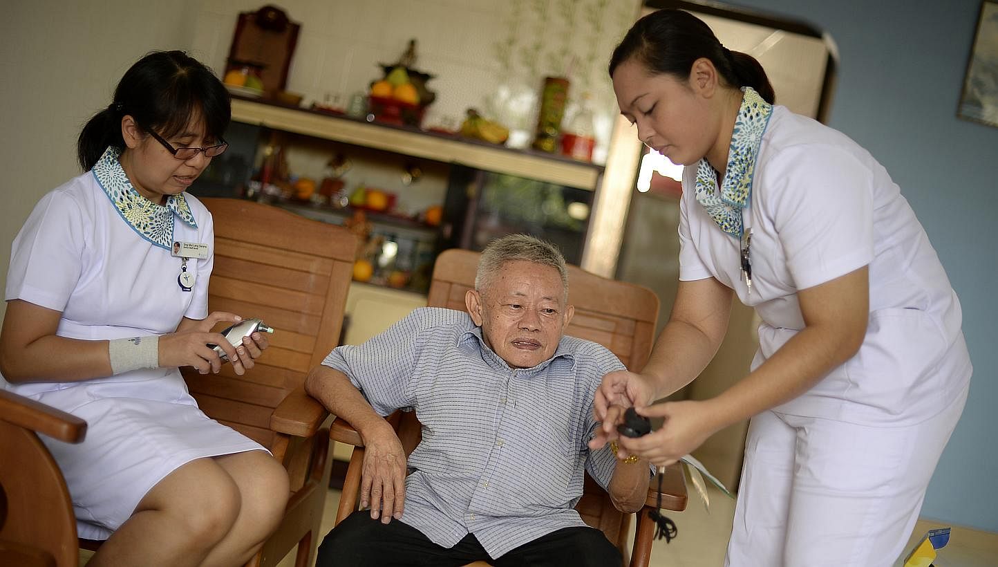 Senior staff nurse Serene Sng (left) and staff nurse Nursetiawati Abdul Rahman visiting Mr Lee Chee Keong, 73, at home to check on him. Mr Lee has breathing difficulties and often ends up in hospital. -- ST PHOTO: MUGILAN RAJASEGERAN