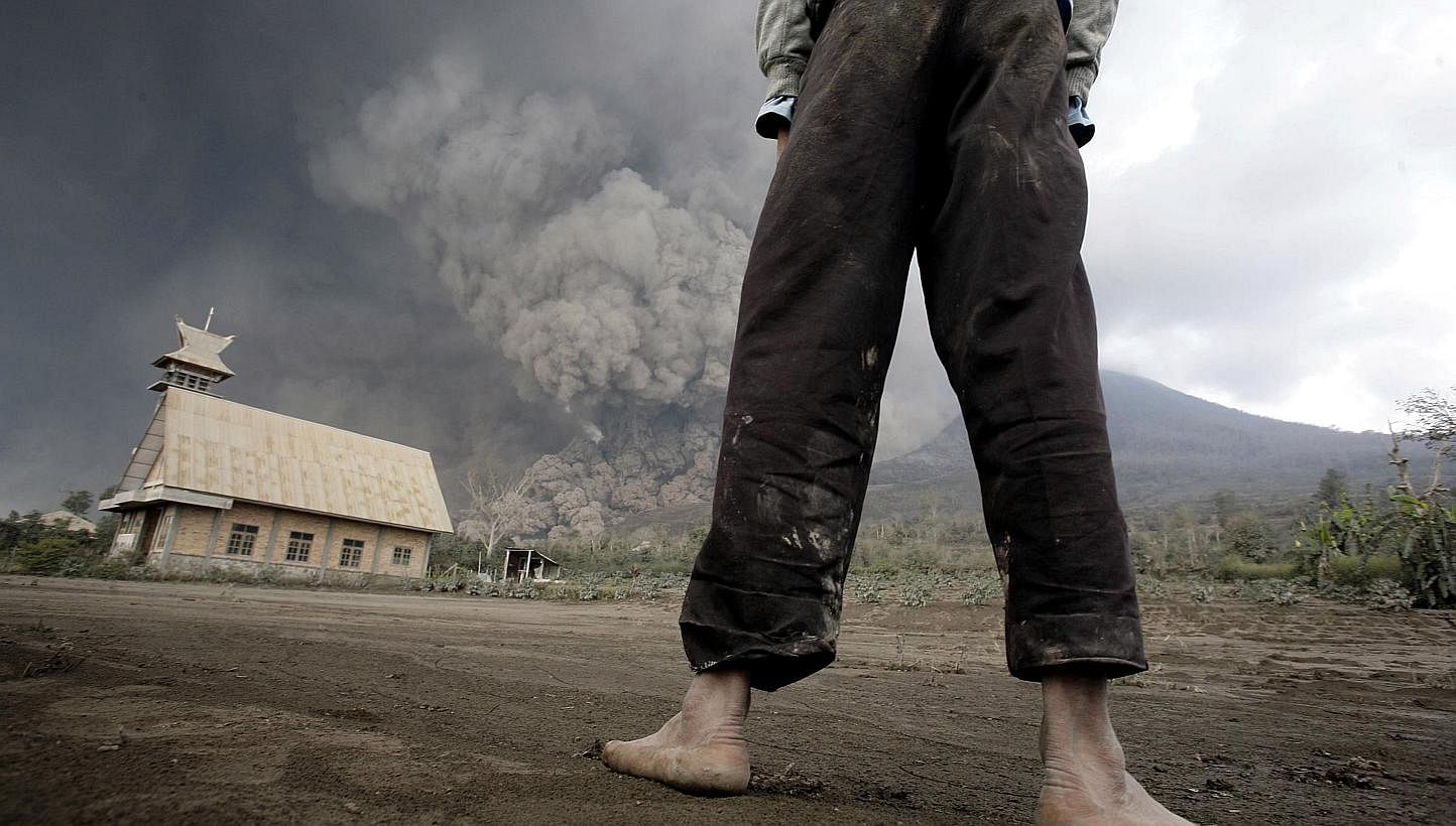 A resident looks on at giant volcanic ash clouds from a village in Karo district during the eruption of Mount Sinabung volcano located in Indonesia's Sumatra island on February 1, 2014. Fourteen people, including four schoolchildren, were killed Febr