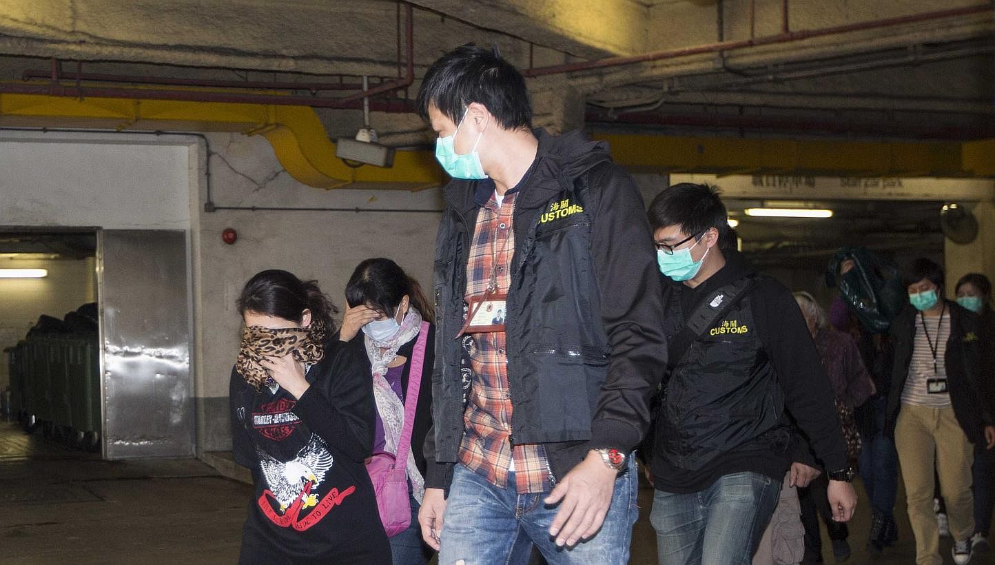 In this file picture of January 3, 2014, Hong Kong Customs officers detain mainlanders who had tried to carry excessive amount of infant formula out of the city, defying the limit of "two tins" per person. Mainlanders have come in droves to smuggle i