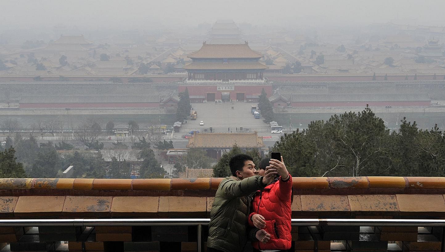 A couple taking a picture of themselves in front of the Forbidden City through thick haze on the top of Jingshan Park in Beijing, March 3, 2014. -- PHOTO: REUTERS