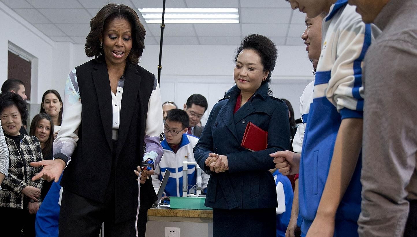 US first lady Michelle Obama (left) tries out a remote-controlled robot next to Peng Liyuan, wife of Chinese President Xi Jinping, during a visit at the Beijing Normal School, a school which prepares students for university abroad, in Beijing, March 