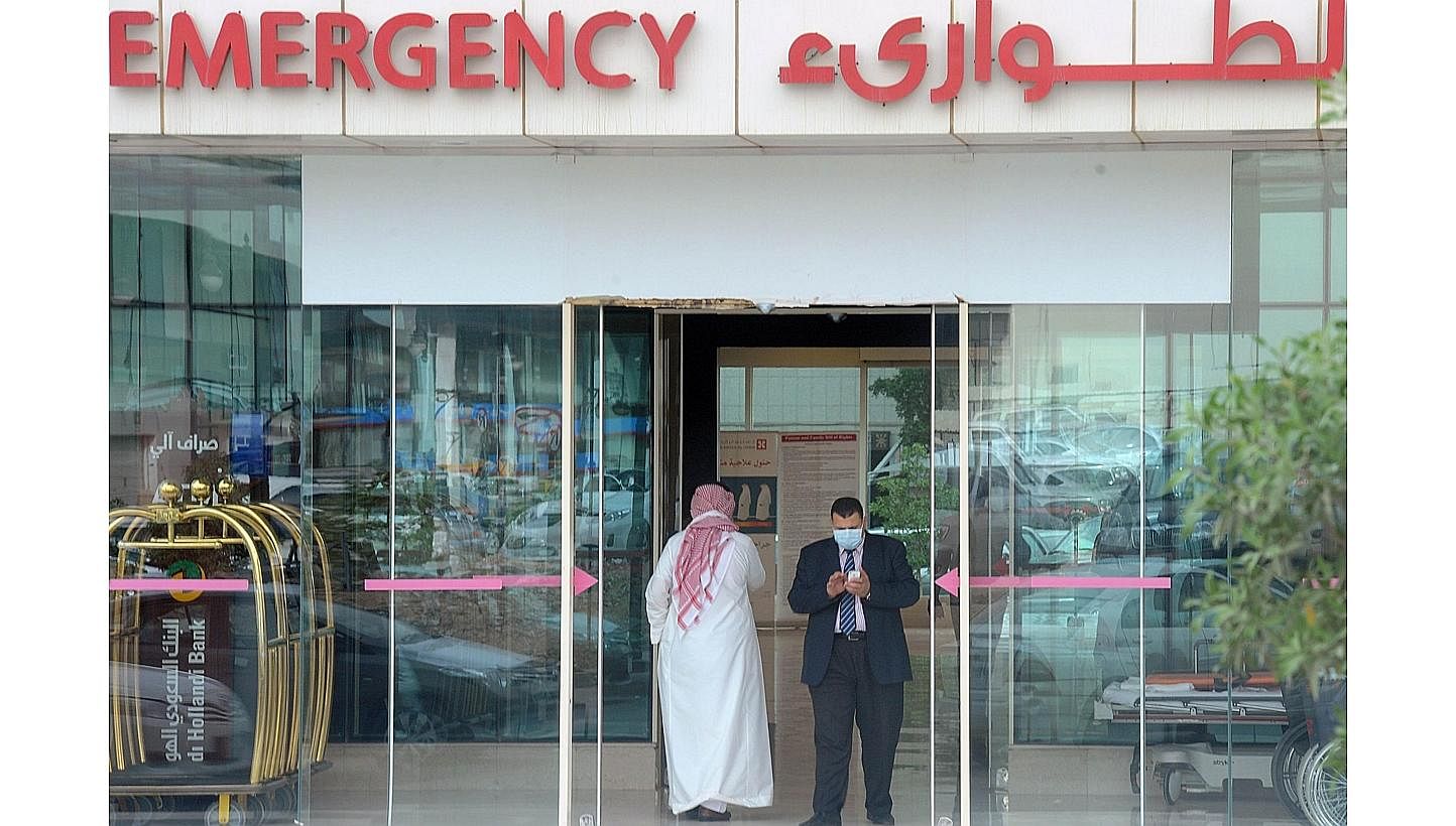A man, wearing a mouth and nose mask, checks his phone as he leaves the hospital's emergency department on April 27, 2014, in the Saudi capital Riyadh.&nbsp;Over the weekend, the death toll for the Middle East Respiratory Syndrome (Mers) topped 100, 