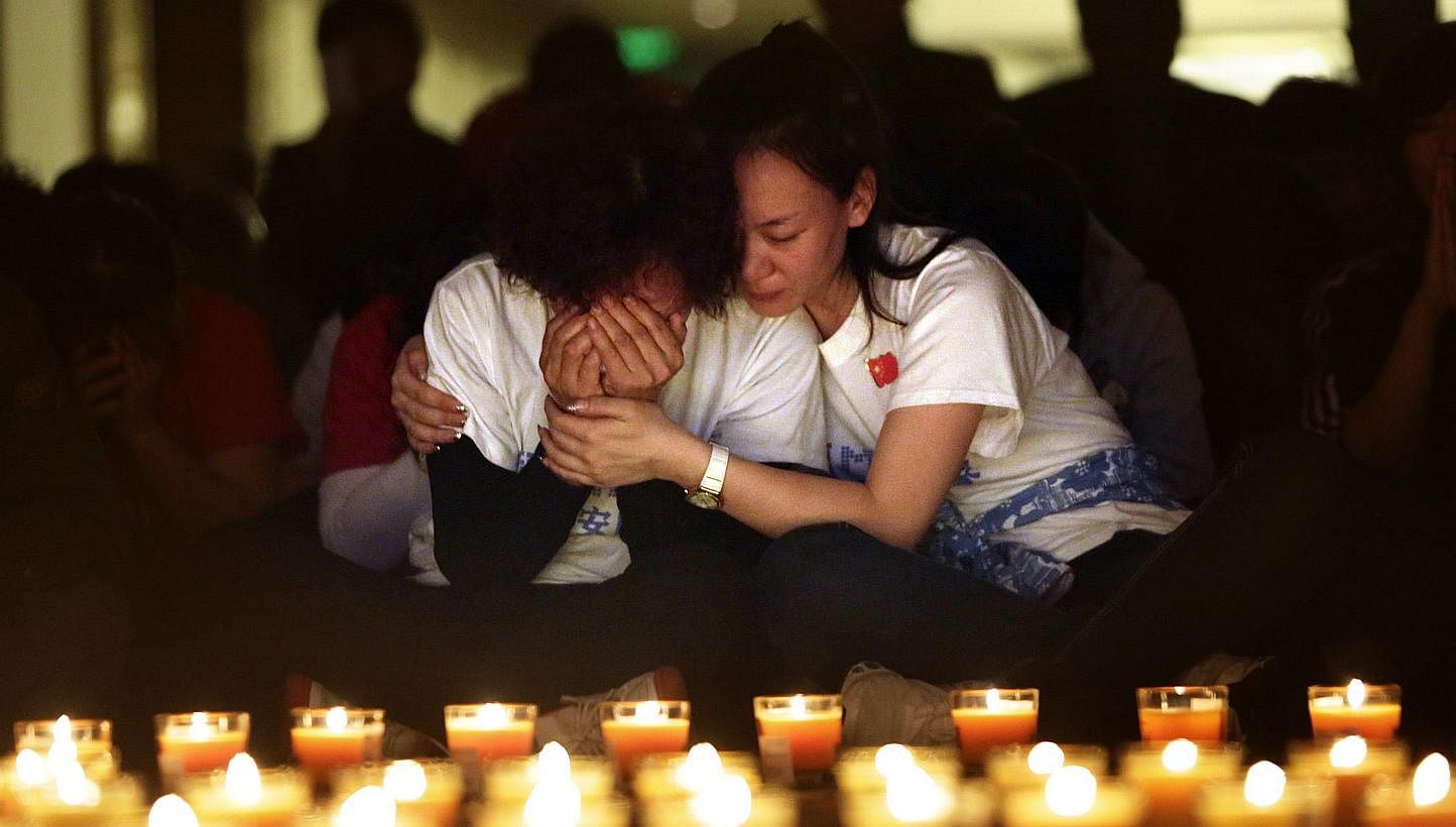 A family member cries as she and other relatives pray during a candlelight vigil for passengers onboard the missing Malaysia Airlines Flight MH370 in the early morning at Lido Hotel in Beijing on April 8, 2014. -- PHOTO: REUTERS