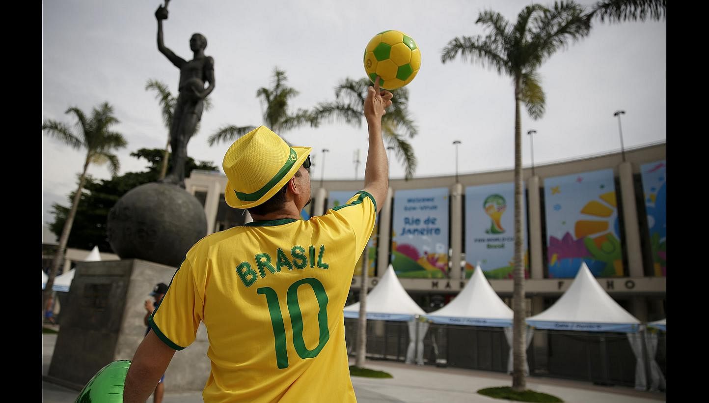 A street busker spinning a ball in Rio de Janeiro ahead of the World Cup. While the party is in full swing in Brazil, stockbrokers in Singapore are expecting commissions to drop by as much as 50 per cent during the World Cup period. -- PHOTO: REUTERS