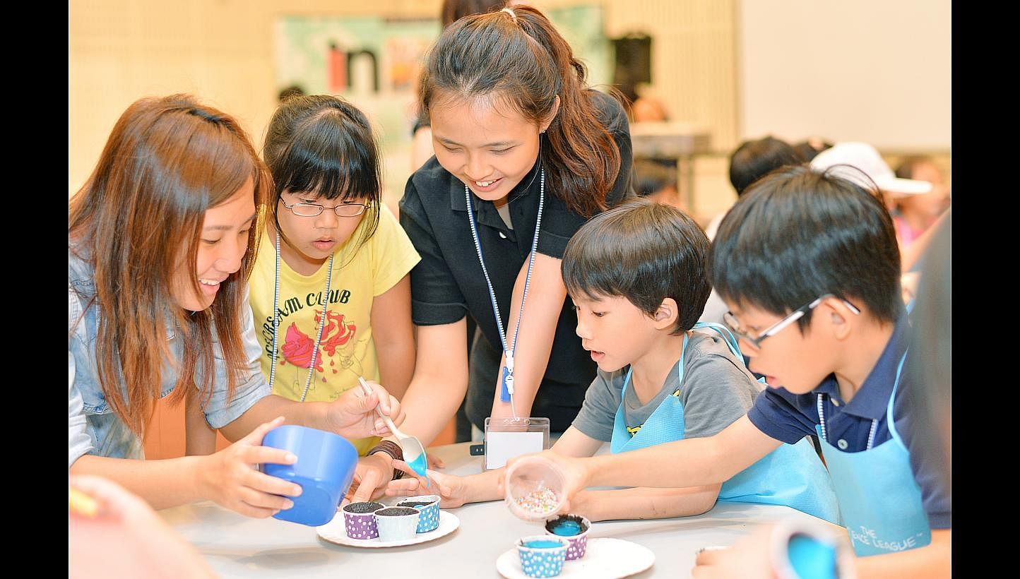 Young participants of the chemistry baking session included Chloe Ho (in yellow), seven, Talon Lee (in grey), six, and Dylan Ho (in blue), nine, seen here getting help to decorate their cupcakes.