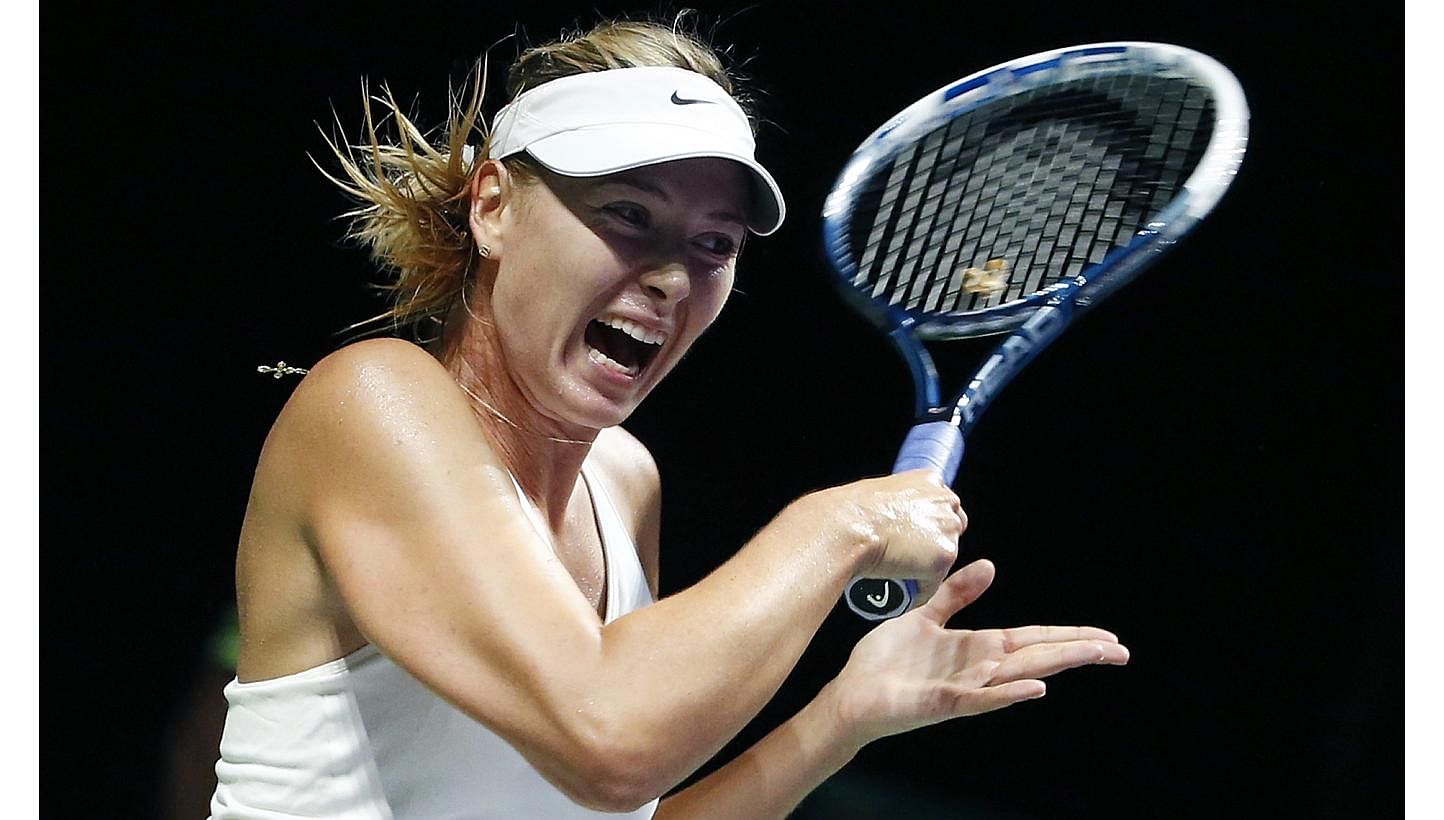 Maria Sharapova of Russia plays a shot against Caroline Wozniacki of Denmark during their WTA Finals singles tennis match at the Singapore Indoor Stadium Oct 21, 2014. -- PHOTO: REUTERS