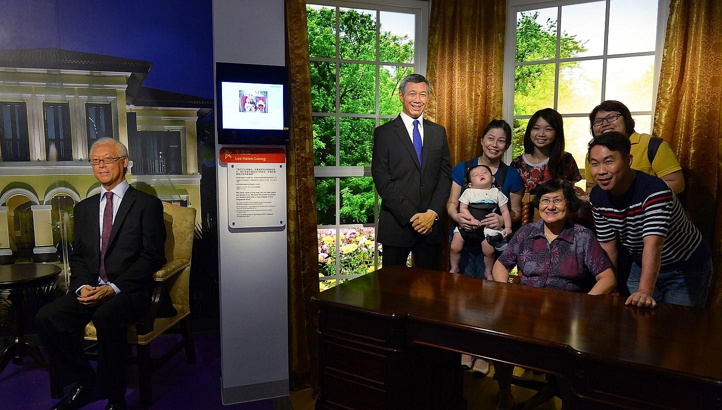 Visitors to Madame Tussauds Singapore pose for a photo with Prime Minister Lee Hsien Loong. The wax figurine of Emeritus Senior Minister Goh Chok Tong is seen on the left. -- ST PHOTO: NG SOR LUAN