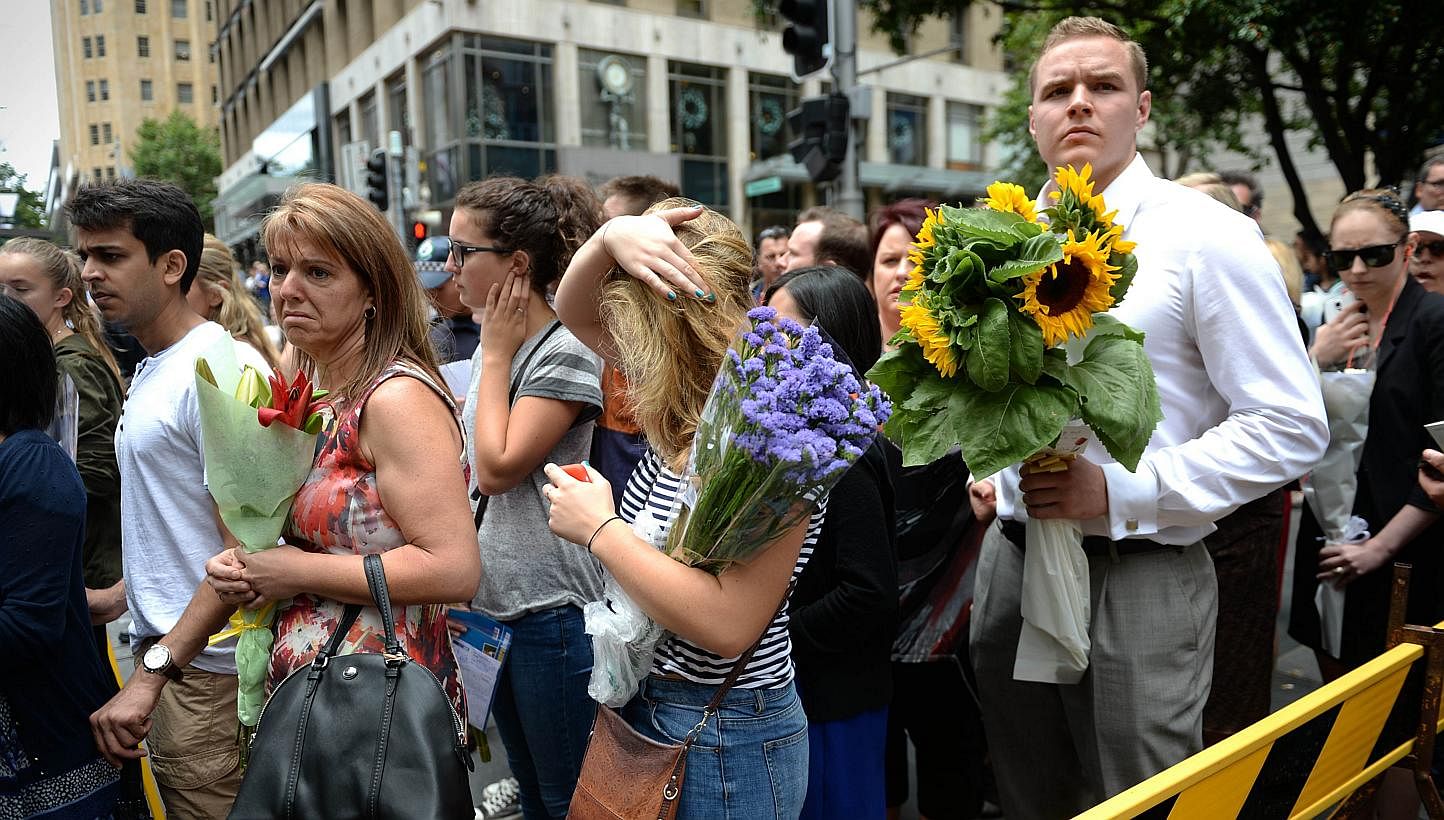 Visitors queue up to lay flowers at a makeshift memorial near the scene of a fatal siege in the heart of Sydney's financial district on Dec 16, 2014. -- PHOTO: AFP