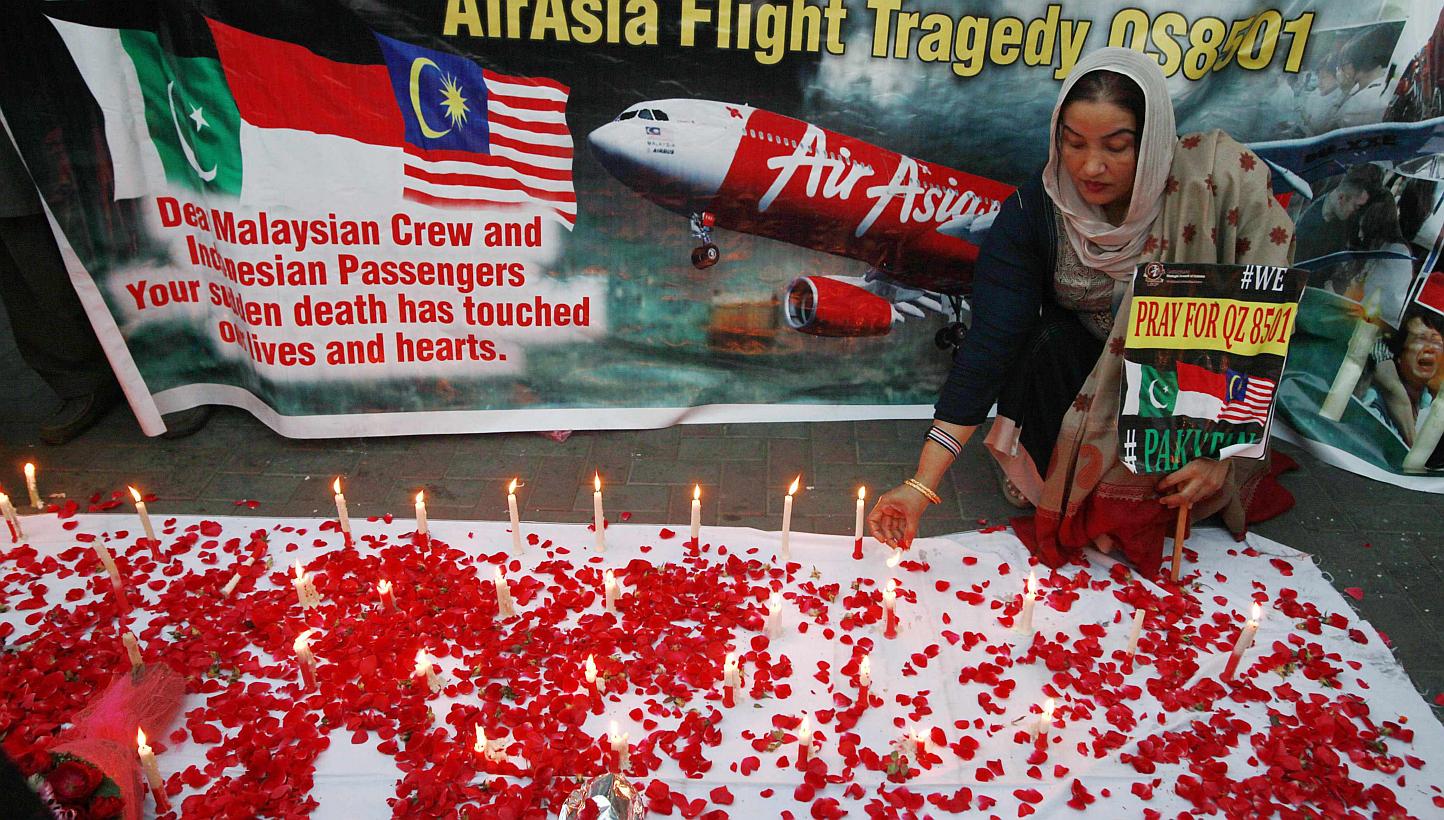 A member of the Lawyers Strategic Council of Pakistan holding up a sign as she lights candles during a vigil for the passengers of AirAsia Flight QZ8501 in Lahore on Jan 2, 2015. -- PHOTO: REUTERS