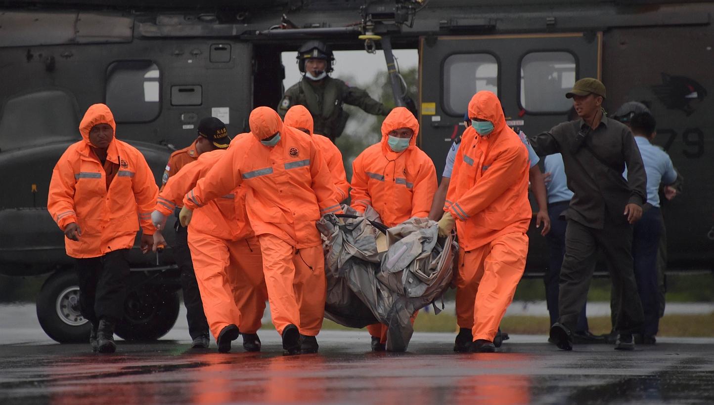 Members of an Indonesian search and rescue team carry items for investigation, found during the search operation for the missing AirAsia flight 8501, after being delivered by a Singapore Super Puma helicopter from the Republic of Singapore Air Force 