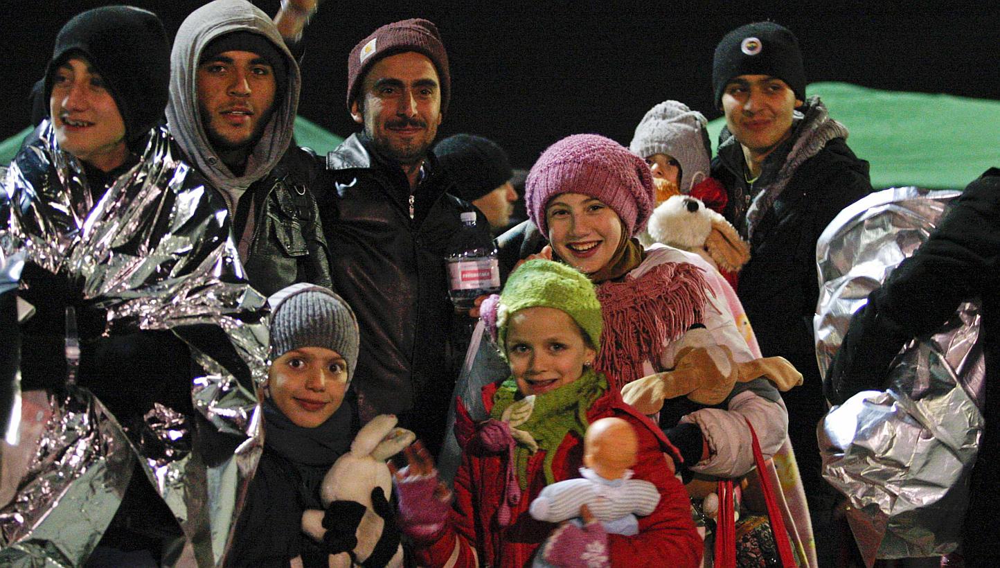 Migrants smile after disembarking from the Sierra Leone-flagged vessel Ezadeen at Corigliano Calabro harbour, southern Italy Jan 3, 2015.&nbsp;&nbsp;Italian authorities disembarked some 360 cold and hungry migrants Saturday from a ship abandoned by i