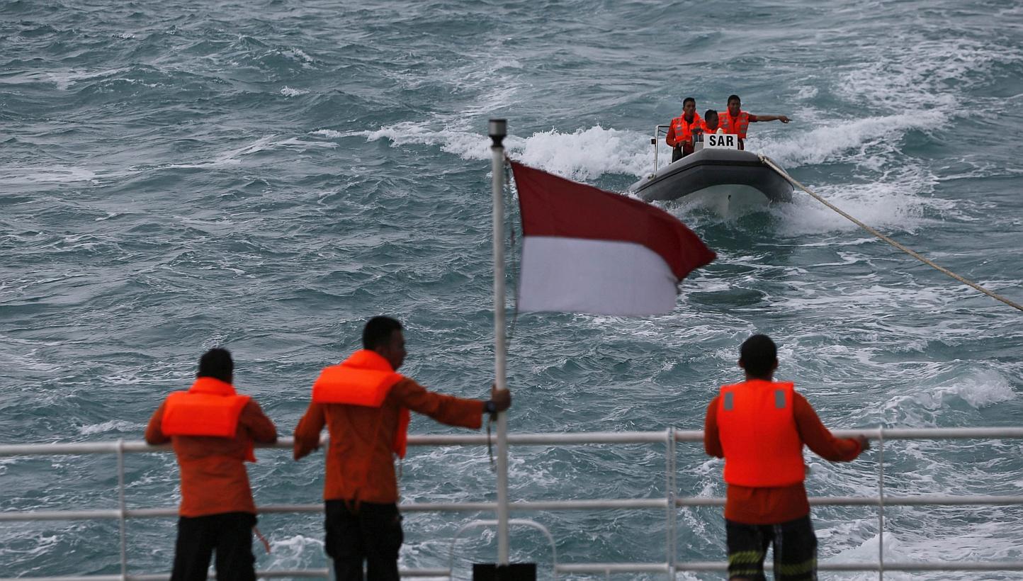Rescue team members in a boat communicate with other members of the team on the deck of the Search and Rescue (SAR) ship KN Purworejo during a search operation for passengers onboard AirAsia Flight QZ8501 in the Java Sea on Jan 4, 2015. -- PHOTO: REU