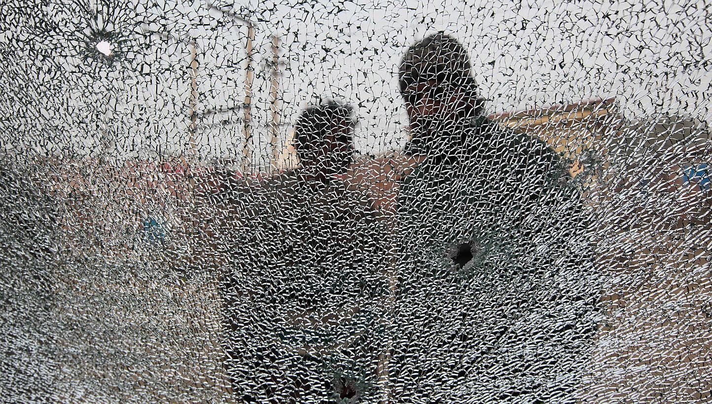 Indian villagers stand alongside the shattered windscreen of a vechile damaged in cross-border firing in the village of Bainglad in the Samba district, some 50km from Jammu, on Jan 3, 2015.&nbsp;Indian and Pakistani troops intensified cross-border fi