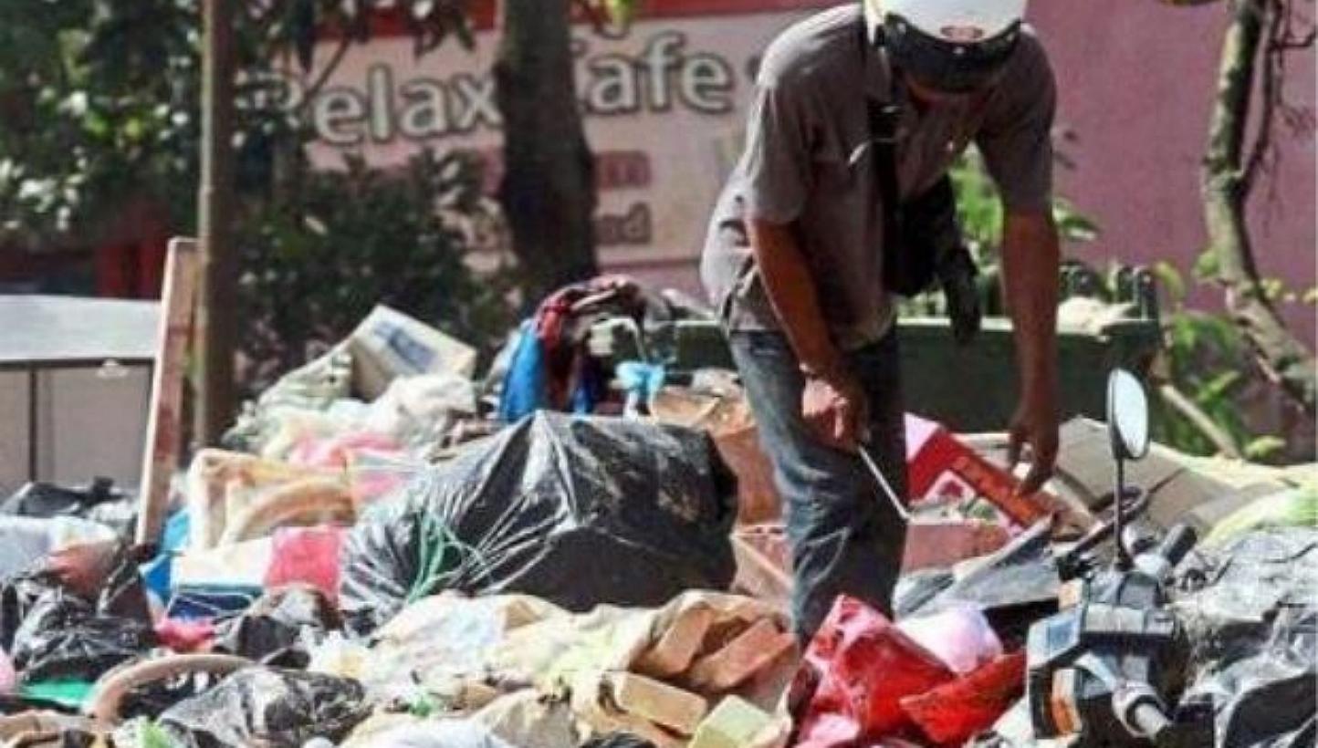 A man sifting through a pile of debris and rubbish accumulated from the floods at Jalan Kutan in Tumpat, Kelantan. -- PHOTO: THE STAR/ASIA NEWS NETWORK