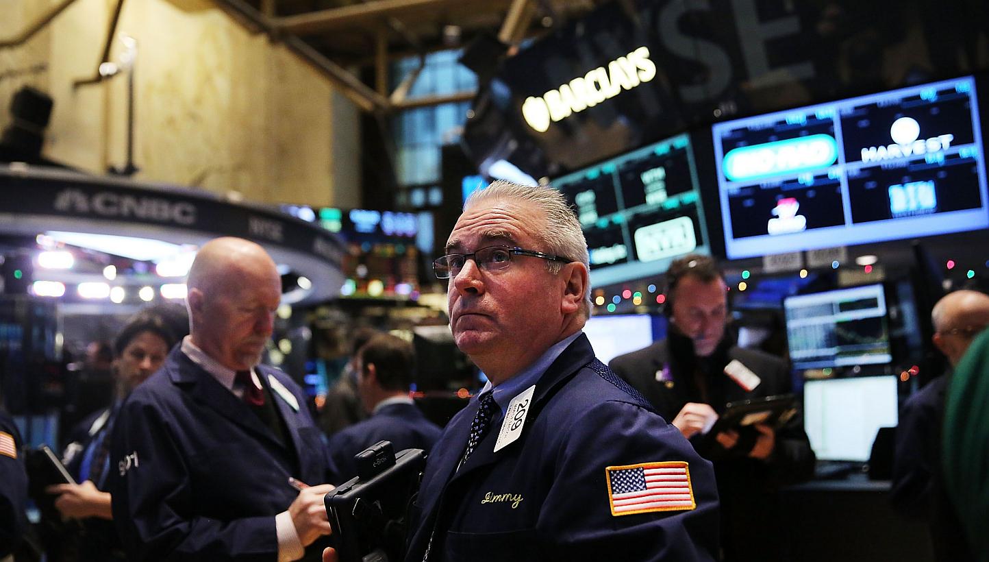 Traders working on the floor of the New York Stock Exchange (NYSE) on Tuesday in New York City. Stocks sank again, partly on fears of a continued fall in global oil prices. -- PHOTO: AFP 