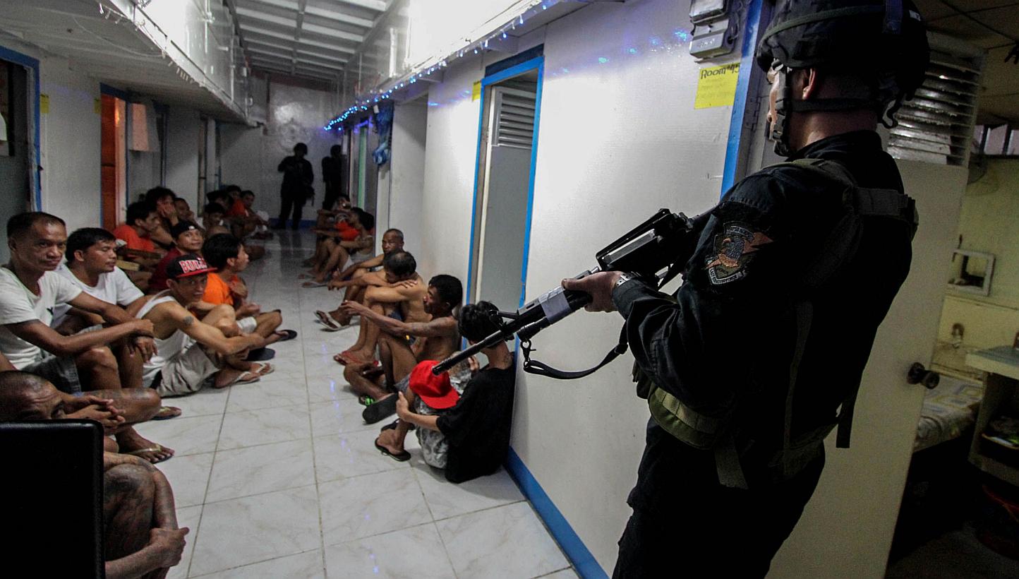 This file photo taken on Dec 16, 2014 shows National Bureau of Investigation (NBI) operatives rounding up inmates inside New Bilibid Prison in Muntinlupa, south of Manila. One inmate was killed and 19 injured in an explosion at a notorious Philippine