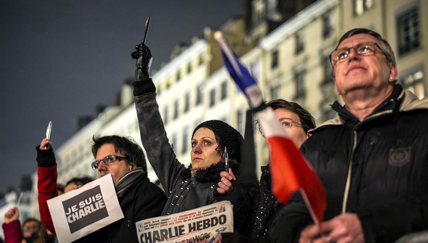 A woman cries as she holds up a pen during a vigil in Lyon on Jan 7, 2015, following an attack by gunmen on the offices of the satirical weekly, Charlie Hebdo, in Paris. A hunt is on for three French nationals suspected to be behind the attack. -- PH