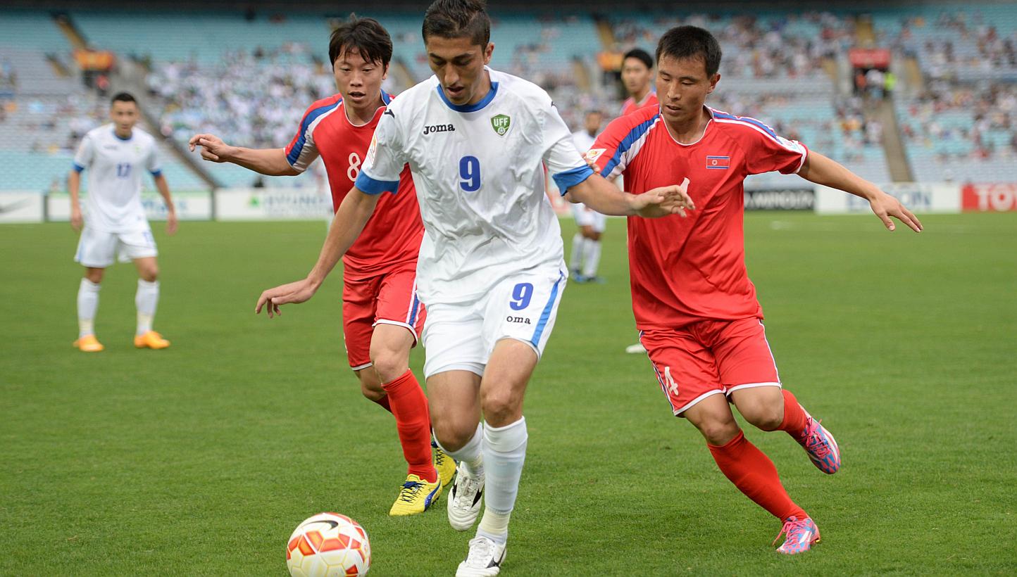 Ryang Yong Gi (left) and Jon Kwang Ik of North Korea (right) challenge Odil Akhmedov of Uzbekistan (centre) for the ball during their Group B football match of the AFC Asian Cup in Sydney on Jan 10, 2015. -- PHOTO: AFP