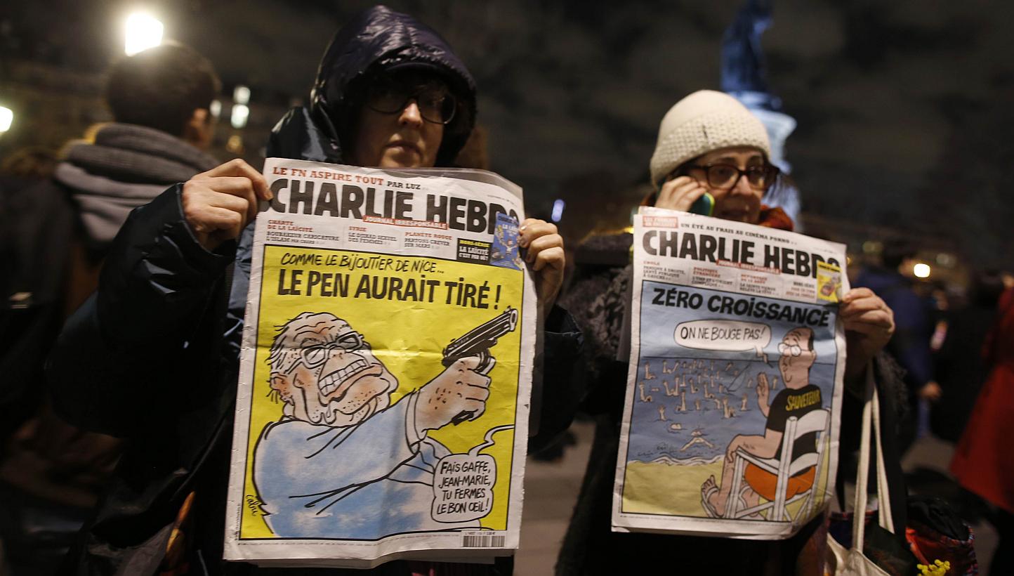 Women hold Charlie Hedbo's frontpages during a gathering on the Place de Republique (Republic square) in Paris, on Jan 8, 2015, as a tribute to the 12 people killed by two gunmen at the French weekly newspaper Charlie Hebdo's editorial office. -- PHO