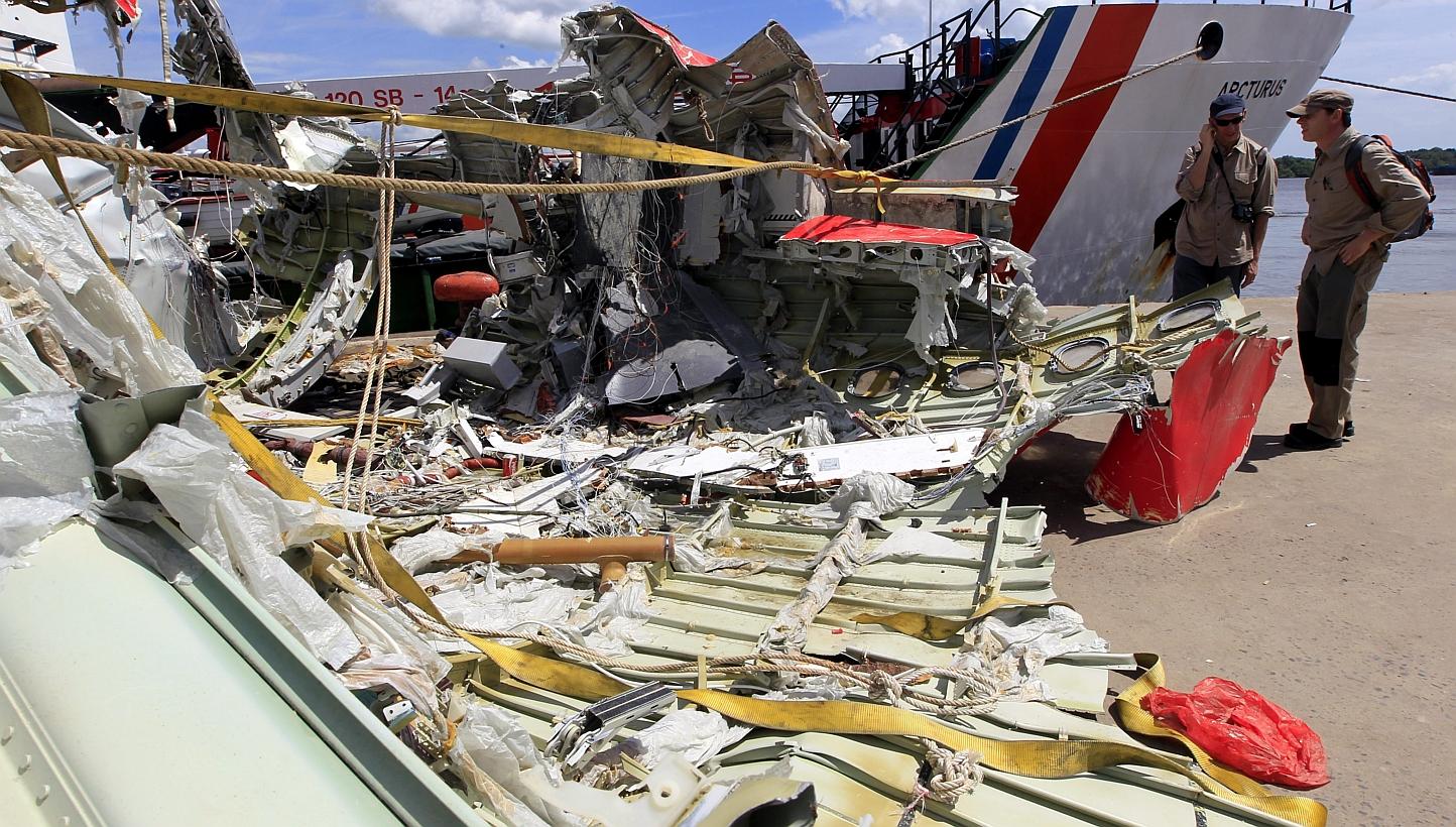 Two foreign investigators talk near debris from the tail of AirAsia flight QZ8501 during the recovery mission at Panglima Utar Kumai Harbour in Kumai, Central Borneo, Indonesia, on Jan 12, 2015.&nbsp;The AirAsia airliner that crashed two weeks ago in