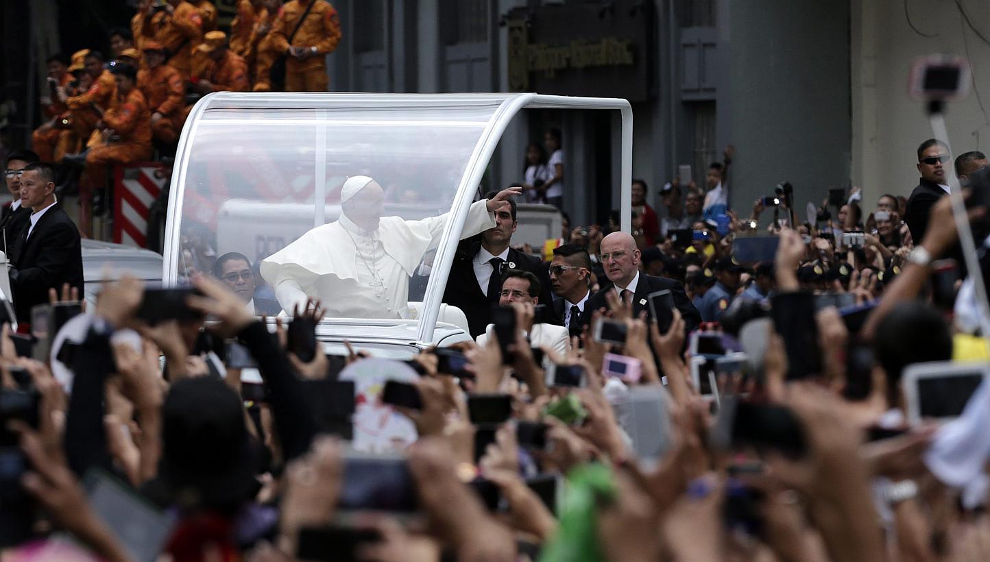 Pope Francis (centre), riding on a 'Popemobile', waves to Filipino well wishers at a street to lead a mass at the Manila cathedral, in Manila, Philippines on Jan 16, 2015. -- PHOTO: EPA