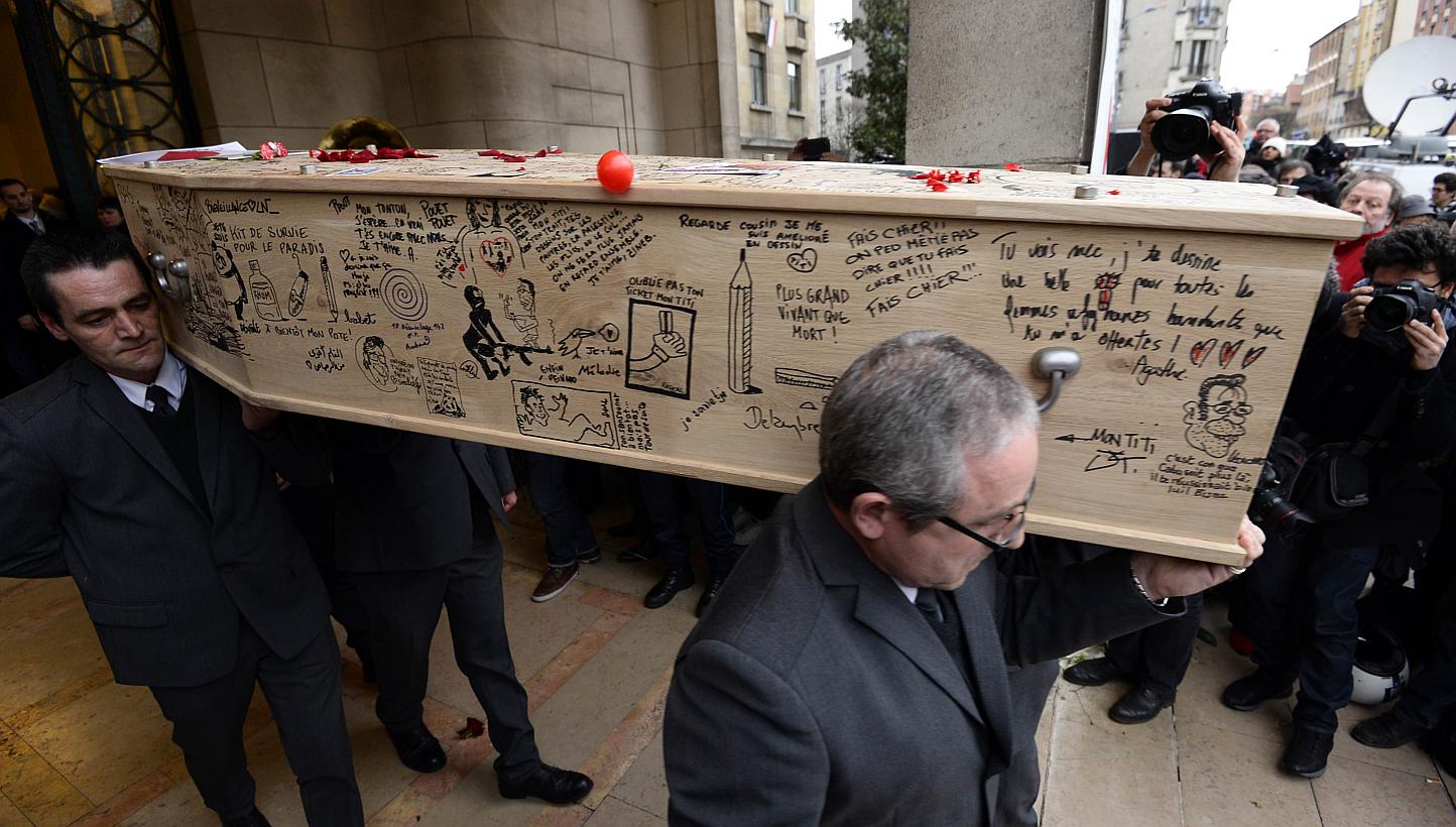 The coffin of cartoonist Bernard "Tignous" Verlhac, 57, one of the 12 people killed in the Jan 7 attack on French satirical weekly Charlie Hebdo, being carried out of the town hall of Montreuil, near Paris, during his funeral on Jan 15, 2015. -- PHOT