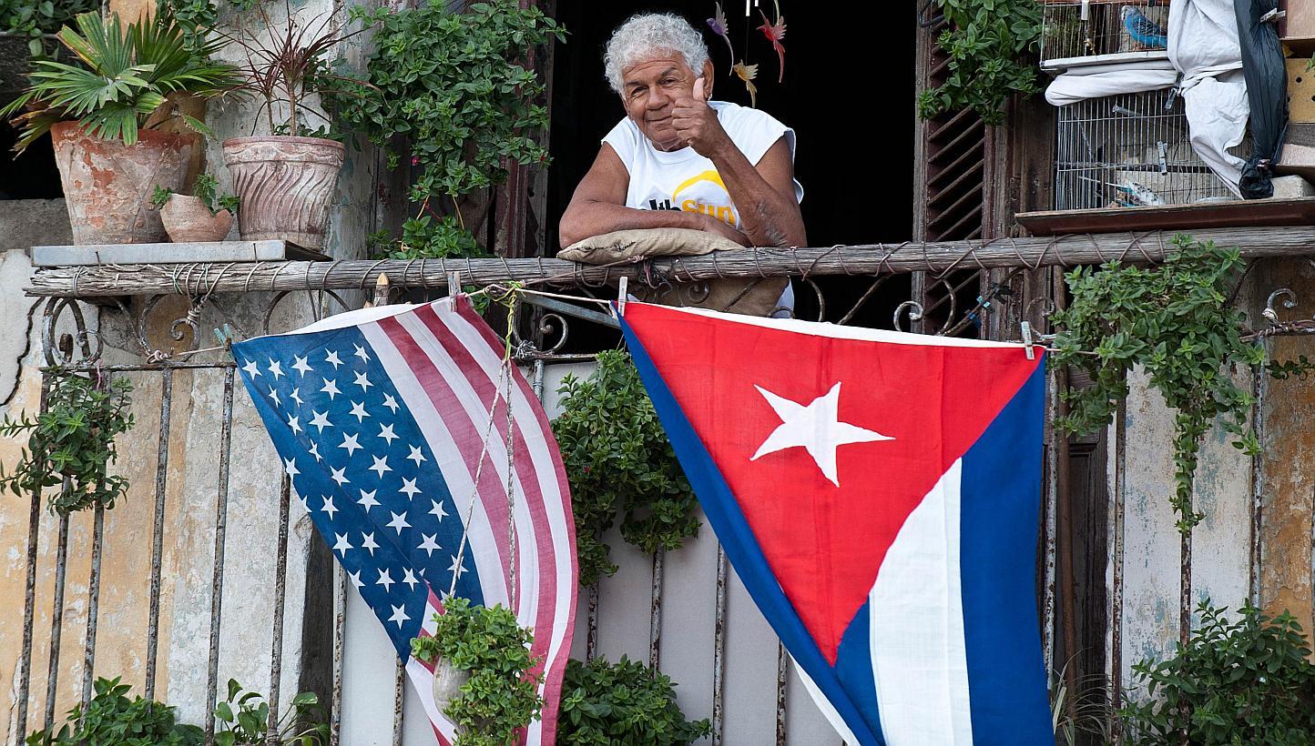 A Cuban gives the thumbs up from his balcony decorated with the US and Cuban flags in Havana, on Jan 16, 2015. -- PHOTO: AFP