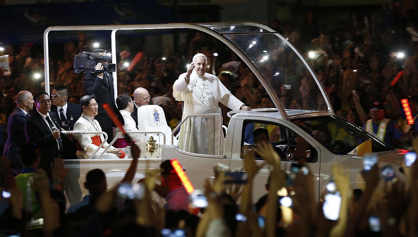 Pope Francis (centre) riding on a 'popemobile' waves to Filipino well wishers in Manila on Thursday. --PHOTO: EPA