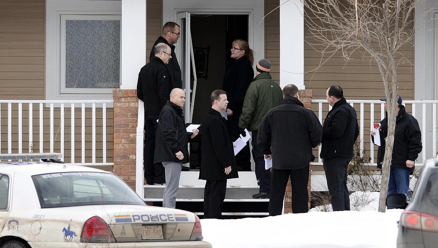 Investigators stand at the door to a home where a suspect who is reported to have shot two Royal Canadian Mounted Police (RCMP) officers at the Apex Casino ended his escape effort, near St. Albert, Alberta on Jan 17, 2015. -- PHOTO: REUTERS&nbsp;
