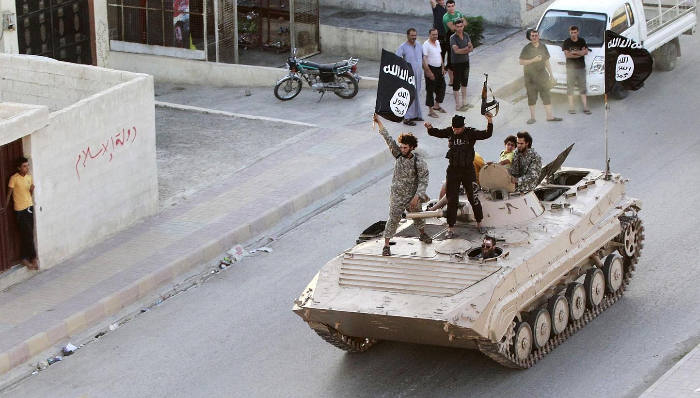 Militant fighters hold the flag of Islamic State in Iraq and Syria (ISIS) while taking part in a military parade along the streets of northern Raqqa province on June 30, 2014. -- PHOTO: REUTERS