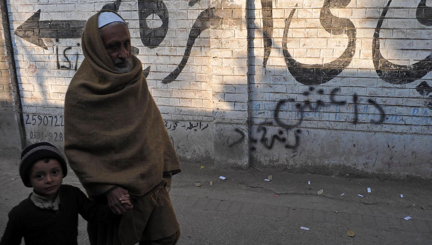 Pakistani pedestrians walk past wall graffiti (bottom) which reads Daesh, the arabic acronym for the Islamic State in Iraq and Syria (ISIS), in Peshawar on Nov 22, 2014.&nbsp;Pakistani security forces have arrested a man they believe is the commander