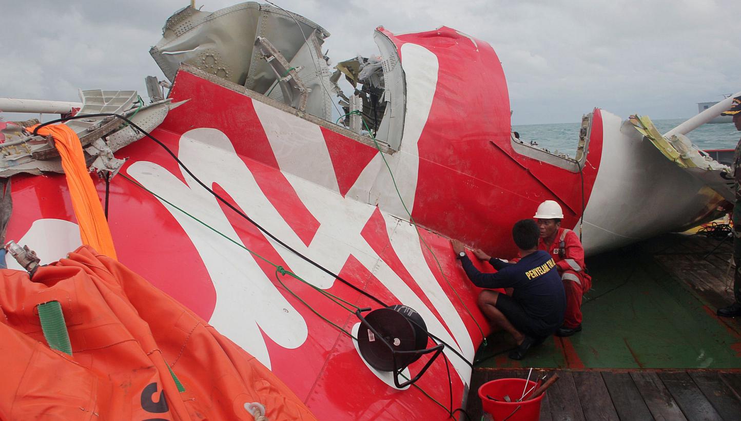 An Indonesian diver and an official examine the wreckage from AirAsia flight QZ8501 after it was lifted into the Crest Onyx ship at sea on Jan 10, 2015. -- PHOTO: AFP
