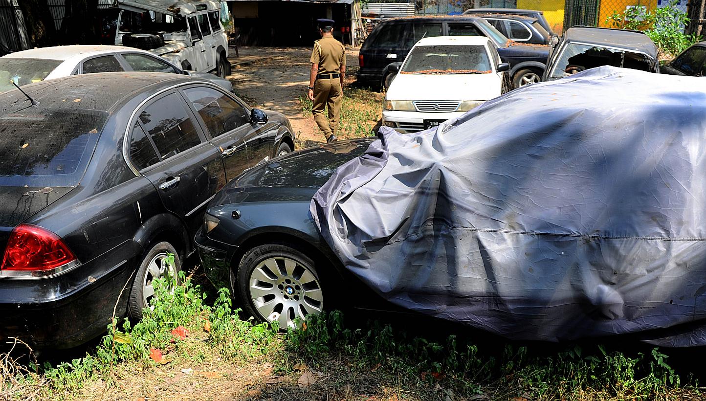 A Sri Lankan police officer walks through a vehicle yard found in the capital Colombo on Jan 23, 2015. Sri Lanka's police Friday seized a fleet of more than 50 state-owned vehicles, including bullet-proof limousines, that were not returned after