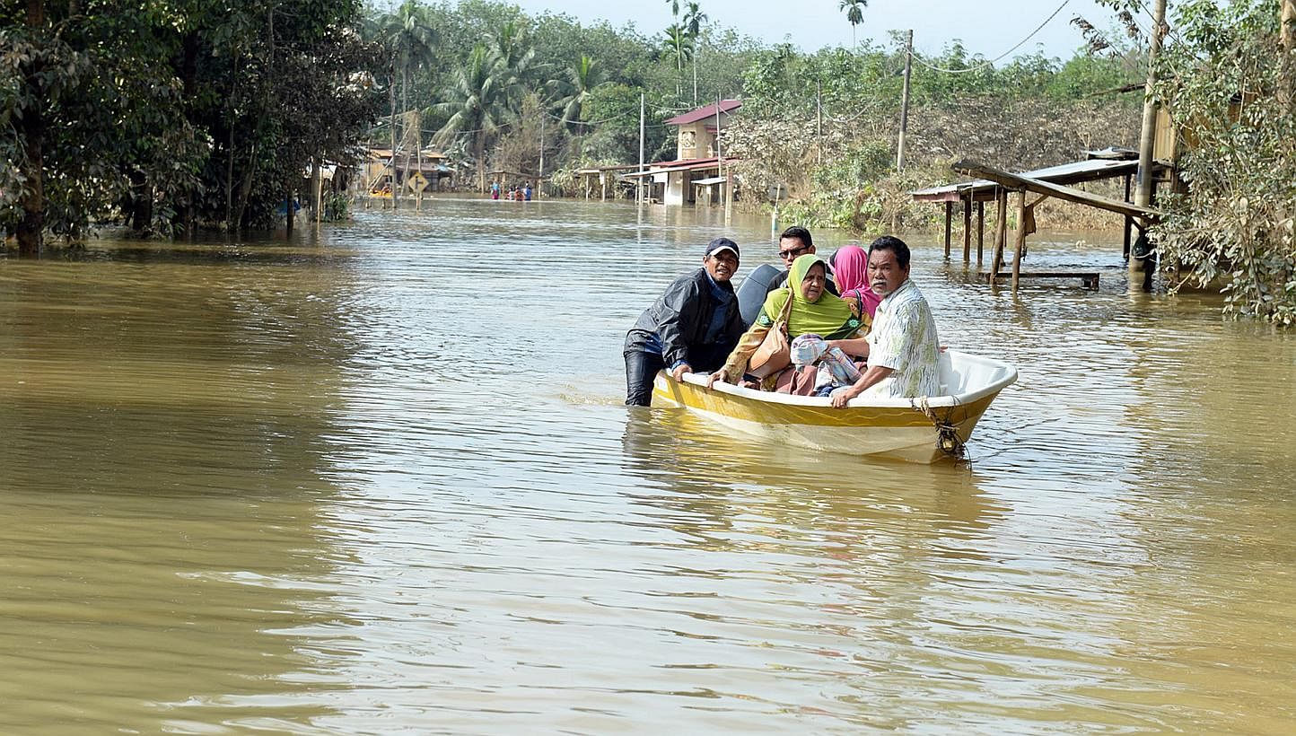 Villagers on their way by boat to get food at a relief centre in Kelantan, Malaysia. A Muslim foundation has raised almost $290,000 in less than a week in aid of the recent catastrophic floods in eastern Malaysia. -- ST PHOTO: AZIZ HUSSIN