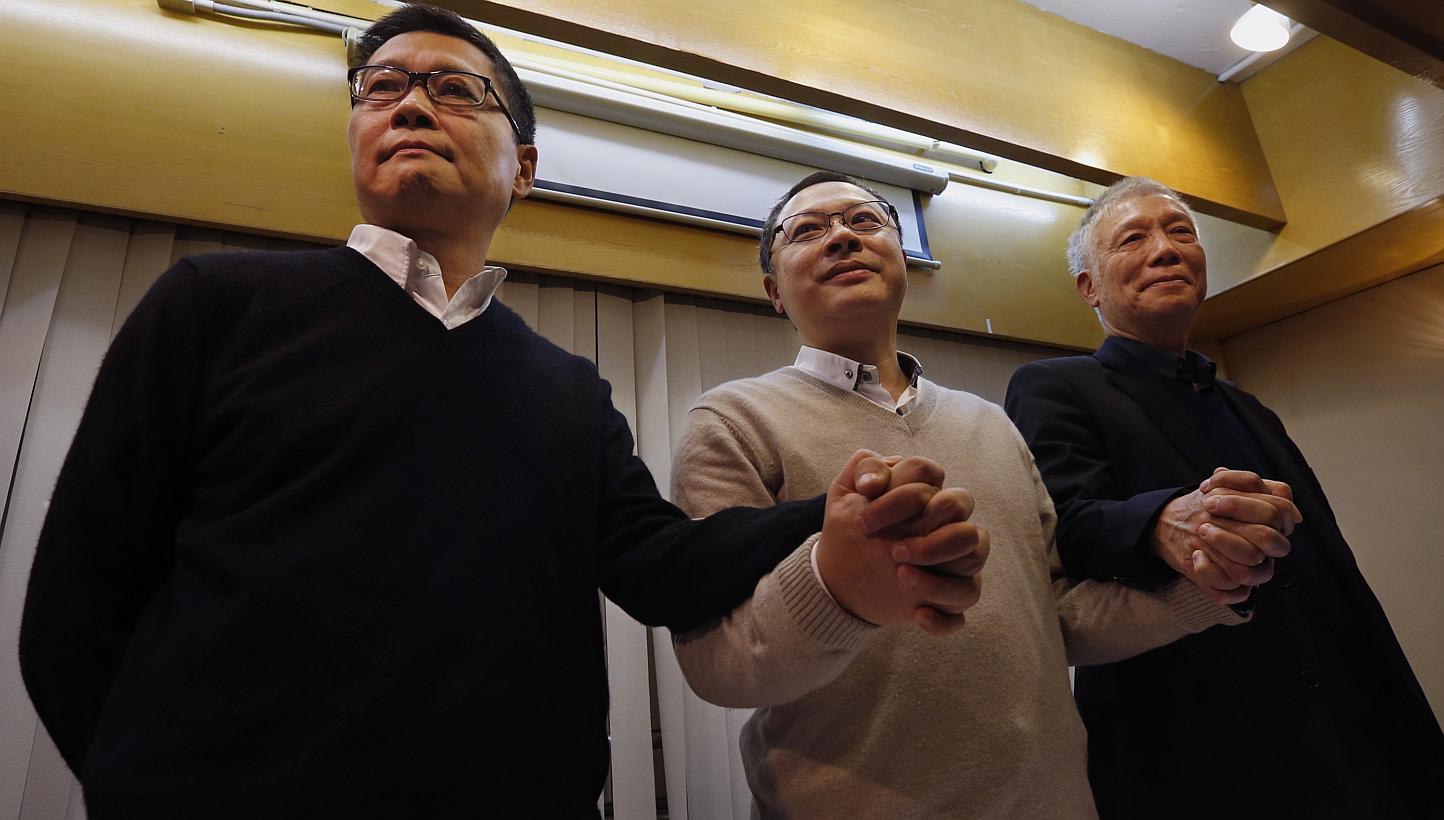 Hong Kong's original Occupy organisers Benny Tai (centre), Chan Kin Man (left) and Chu Yiu Ming joining hands during a news conference on their voluntary surrender to the police, on Dec 2, 2014. -- PHOTO: REUTERS