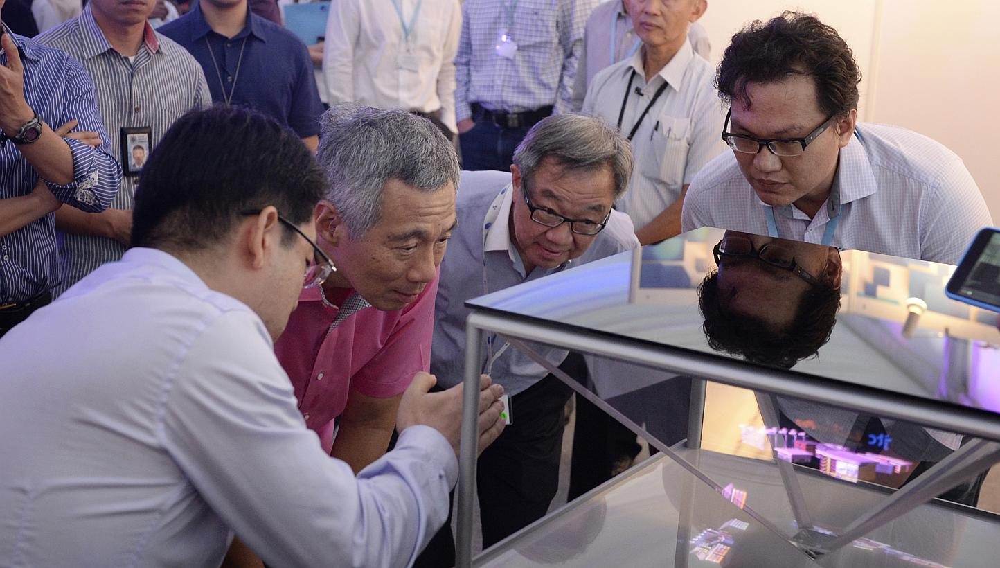 PM Lee takes a close look at a 3D holographic display system prototype with (from left) Spectral Reality director Bernard Song, JTC Corporation chairman Loo Choon Yong and Rock Nano Global CEO Ang Chong Lai.