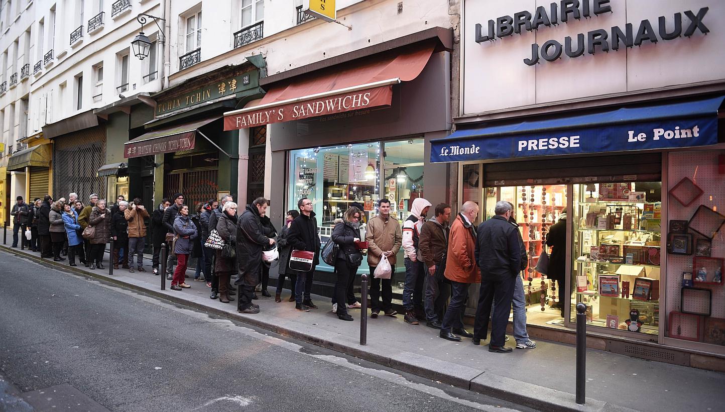 People waiting outside a newsagents in Paris on Jan 14, 2015 as the latest edition of French satirical magazine Charlie Hebdo goes on sale. -- PHOTO: AFP