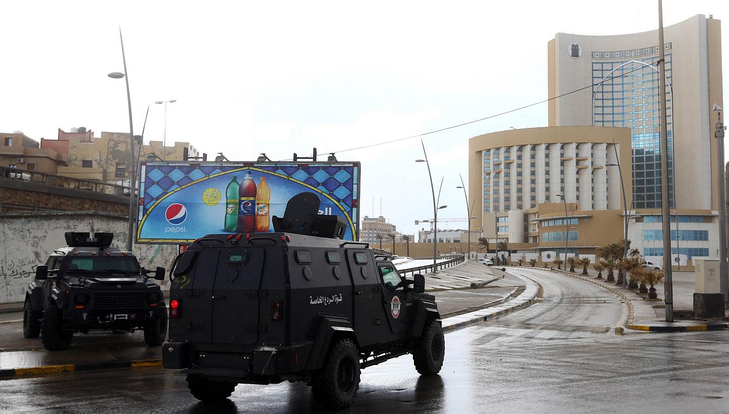 Libyan security forces and emergency services near the Corinthia Hotel (right) in Tripoli on Jan 27, 2015,&nbsp;after Islamic State in Iraq and Syria (ISIS) fighters said they staged an attack on it. -- PHOTO: AFP