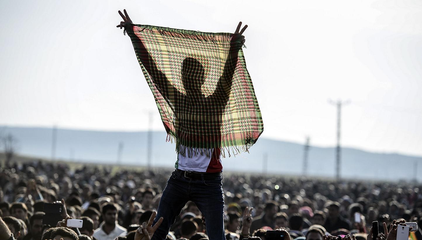 Kurdish people flash the V for victory sign during a celebration rally near the Turkish-Syrian border at Suruc on Tuesday, after ISIS group militants were expelled from the Syrian border town of Kobane, dealing a key symbolic blow to the extremists' 