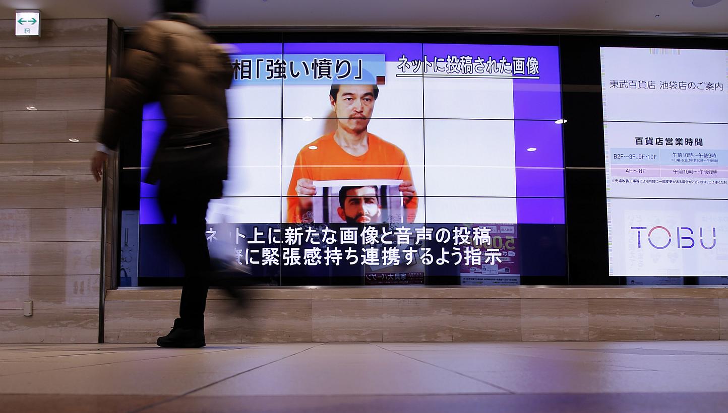 Man walks past television screens displaying a news program, about an Islamic State video showing Japanese captive Kenji Goto, on a street in Tokyo on Jan 28, 2015. -- PHOTO: REUTERS