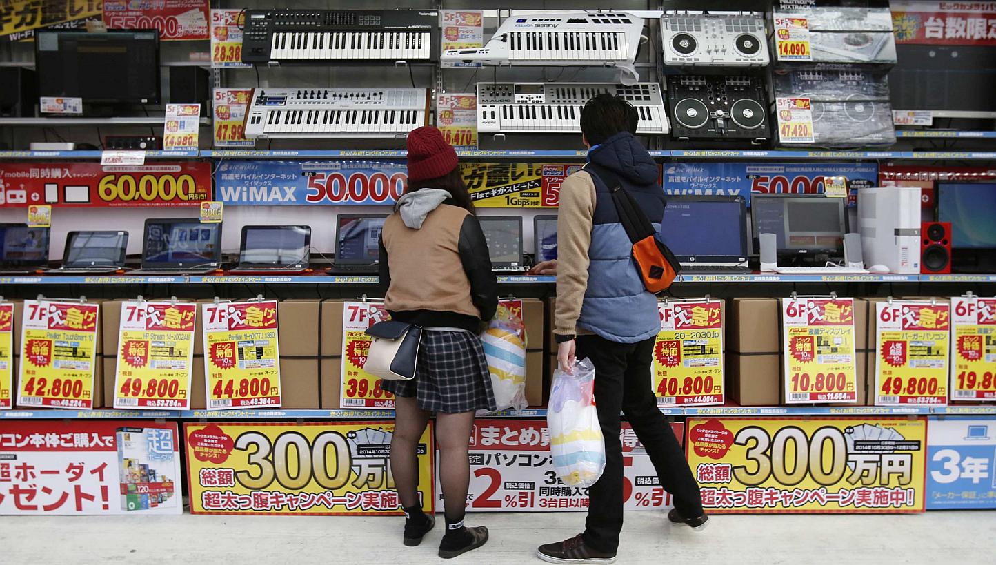 People trying out laptops displayed at an electronics retail store in Tokyo on Nov 16, 2014. Japanese retail sales unexpectedly fell in December, underscoring challenges to Prime Minister Shinzo Abe's effort to stoke a recovery in the world's third-b