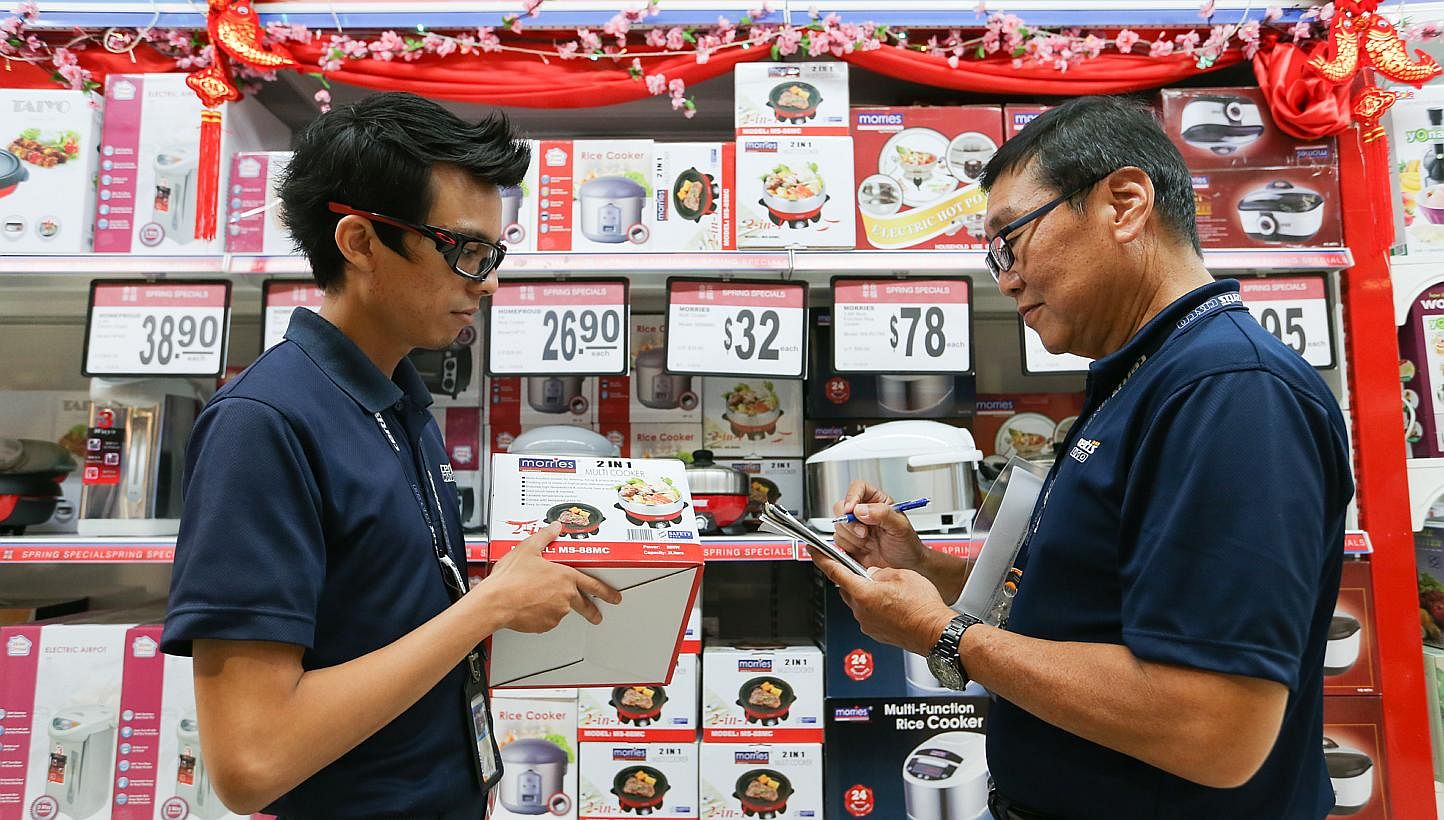 Certis Cisco enforcement officers, Mr Safiuddin Bin Roshan (left) and Mr Wee Peng Soon checking for the Safety Mark sticker on electronic products sold in NTUC. -- ST PHOTO: ONG WEE JIN