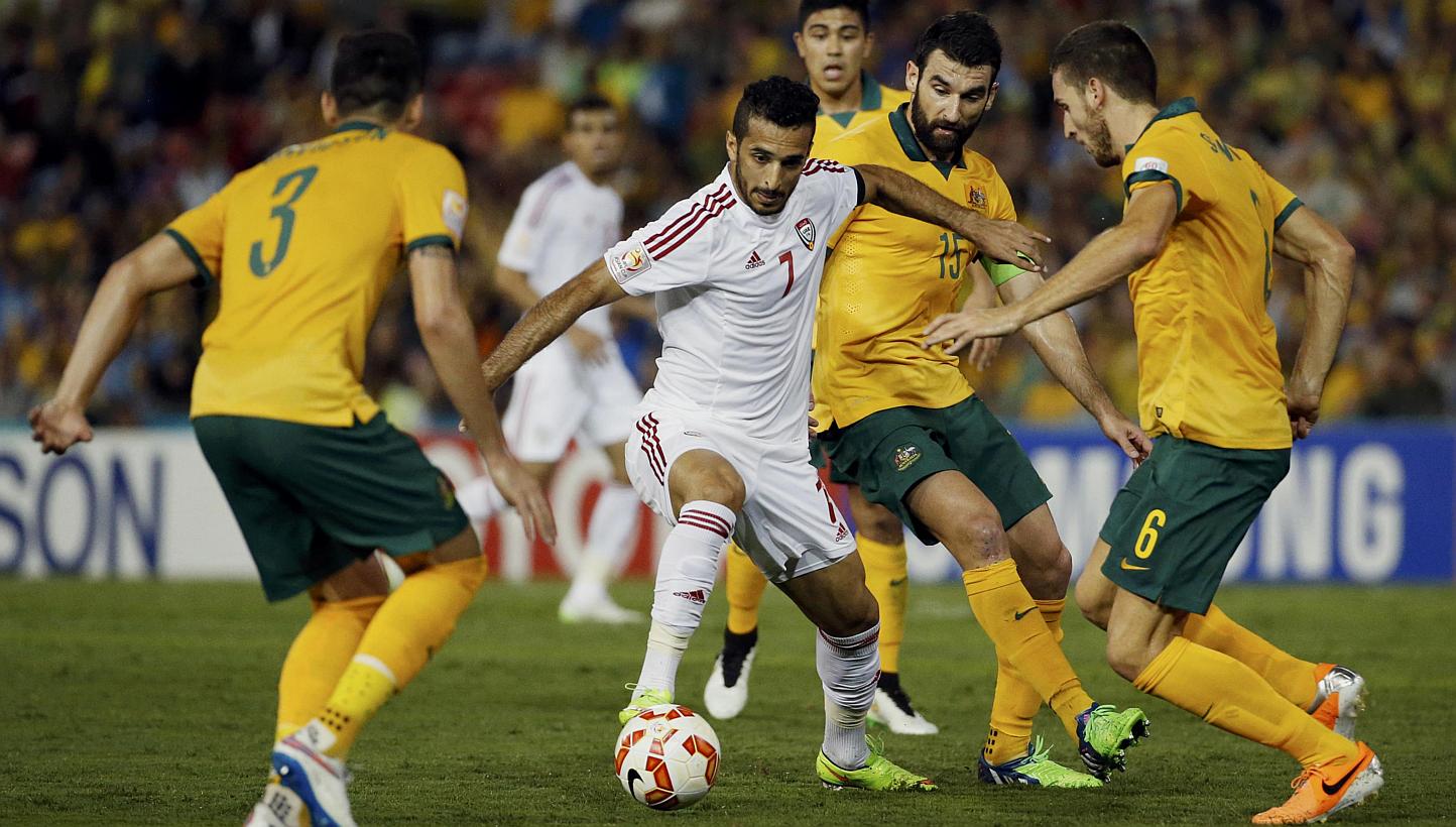 UAE's Ali Mabkhout fights for the ball with Australia's Jason Davidson (left), Mile Jedinak (2nd right) and Matthew Spiranovic (right) during their Asian Cup semi-final soccer match at the Newcastle Stadium in Newcastle on Jan 27, 2015. -- PHOTO: REU