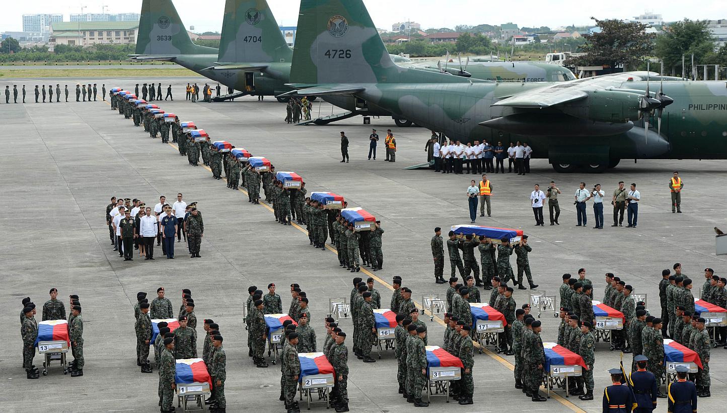 Philippine police commandos carrying the flag-draped coffins of their fallen comrades from C-130 planes shortly after arriving at a military base in Manila on Jan 29, 2015. -- PHOTO: AFP 