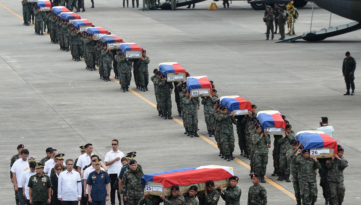 Philippine police commandos carrying the flag-draped coffins of their fallen comrades from C-130 planes shortly after arriving at a military base in Manila on Jan 29, 2015. As many as 44 commandos were killed. -- PHOTO: AFP&nbsp;