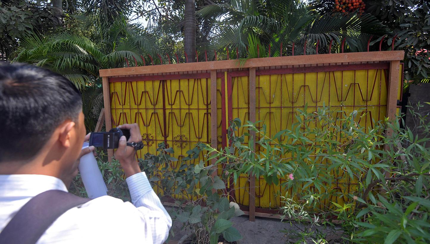 A journalist films an old gate of the Chairman of National League for Democracy (NLD) Aung San Suu Kyi's residence in Yangon on Jan 31, 2015. -- PHOTO: AFP